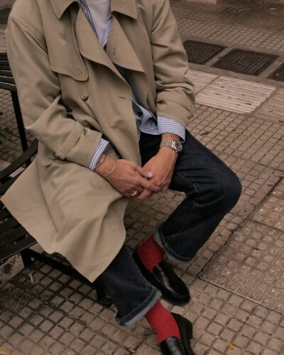 Man wearing beige trench coat with statement text on the back